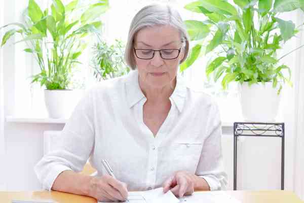© agenturfotografin - stock.adobe.com Ältere Dame bearbeitet Unterlagen